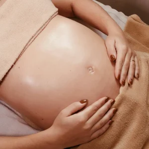 Femme enceinte allongée sur une table de massage pendant une séance d’accompagnement périnatal