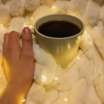 Ambiance cosy avec tasse de café et plaid pour représenter un moment de pause à domicile pour les jeunes parents